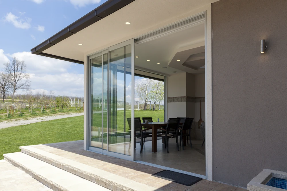 Maison contemporaine avec grande baie vitrée coulissante ouverte sur terrasse dallée