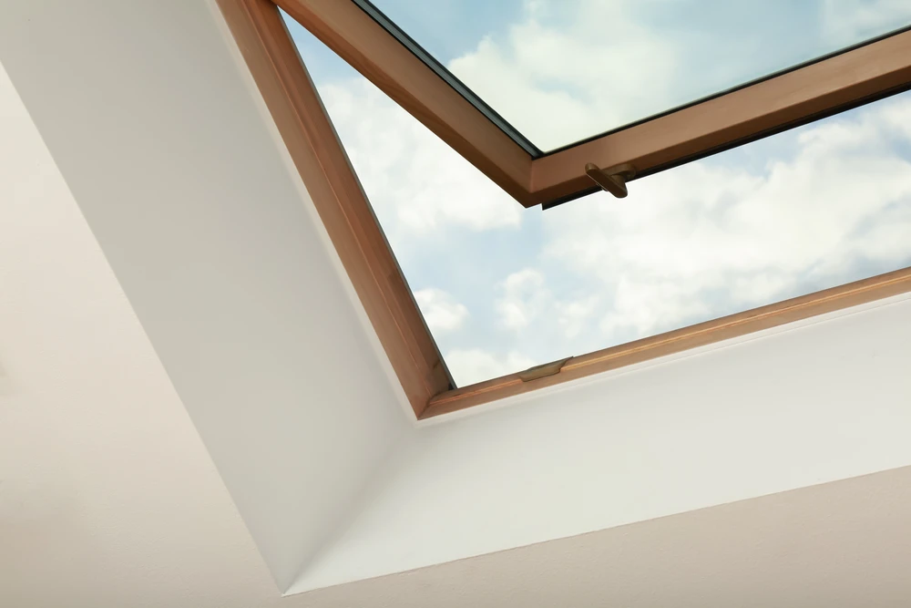Intérieur d'une maison sous combles avec fenêtre de toit ouverte laissant entrer la lumière naturelle