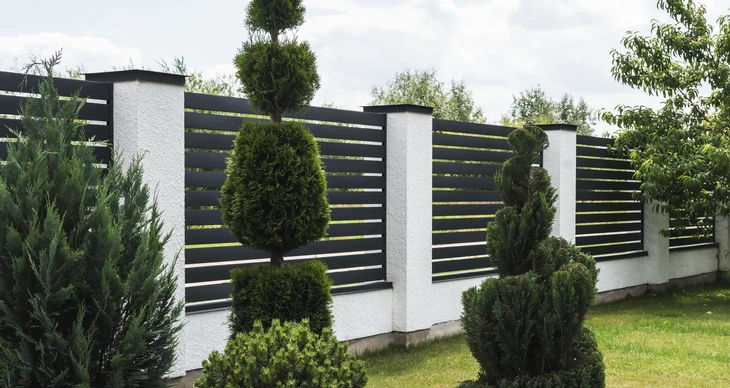 Extérieur résidentiel avec clôture moderne en panneaux composites gris et poteaux blancs